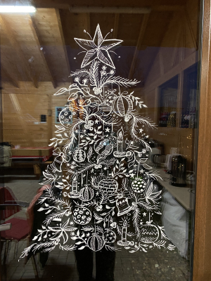 Weihnachtlich bemaltes Fenster im Christbaumdorf Klug mit stilisiertem Tannenbaum als Dekoration