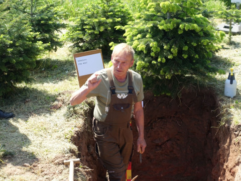 Foto von Dieter Knakowski, der bei den Feldtagen die Bodenschichten in einem Bodenprofil erklärt