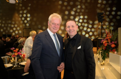 Alois Rainer, Bundesminister für Landwirtschaft, Ernährung und Heimat mit Uwe Klug 1. Vorsitzender des Christbaumdorf Mittelsinn e. V. bei der Taspo Award Gala 2025 in Berlin in festlicher Abendgarderobe vor beleuchtetem Hintergrund mit goldenen Lichtern