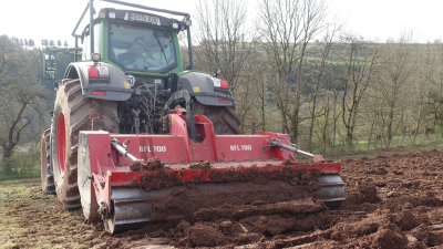 Traktor mit angebauter Bodenfräse bei der Bodenbearbeitung Bodenfräse zerkleinert Restholz und arbeitet Mulchmaterial in den Boden ein