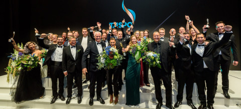 Taspo Award 2023 – Christbaum-Klug gewinnt in Umwelt & Nachhaltigkeit Große Gruppe von Menschen in Abendgarderobe steht auf einer Bühne und hält Pokale und Blumensträuße in die Höhe