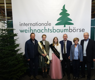 Inthronisierung der Christbaumkönigin auf der internationalen Weihnachtsbaumbörse Sieben Personen stehen vor einem großen Banner mit der Aufschrift „internationale Weihnachtsbaumbörse“